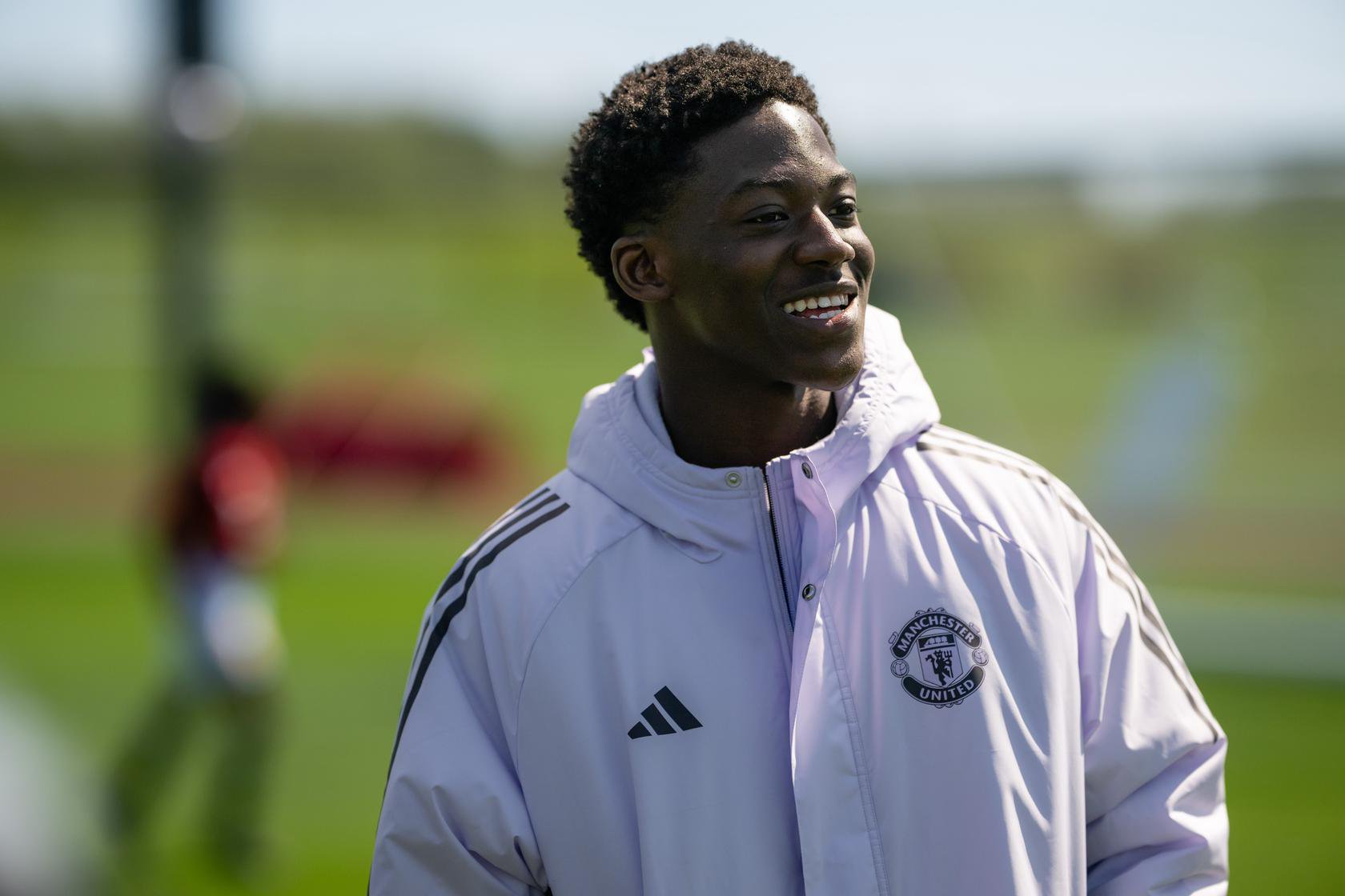 Kobbie Mainoo smiling while doing soccer school with Academy kids