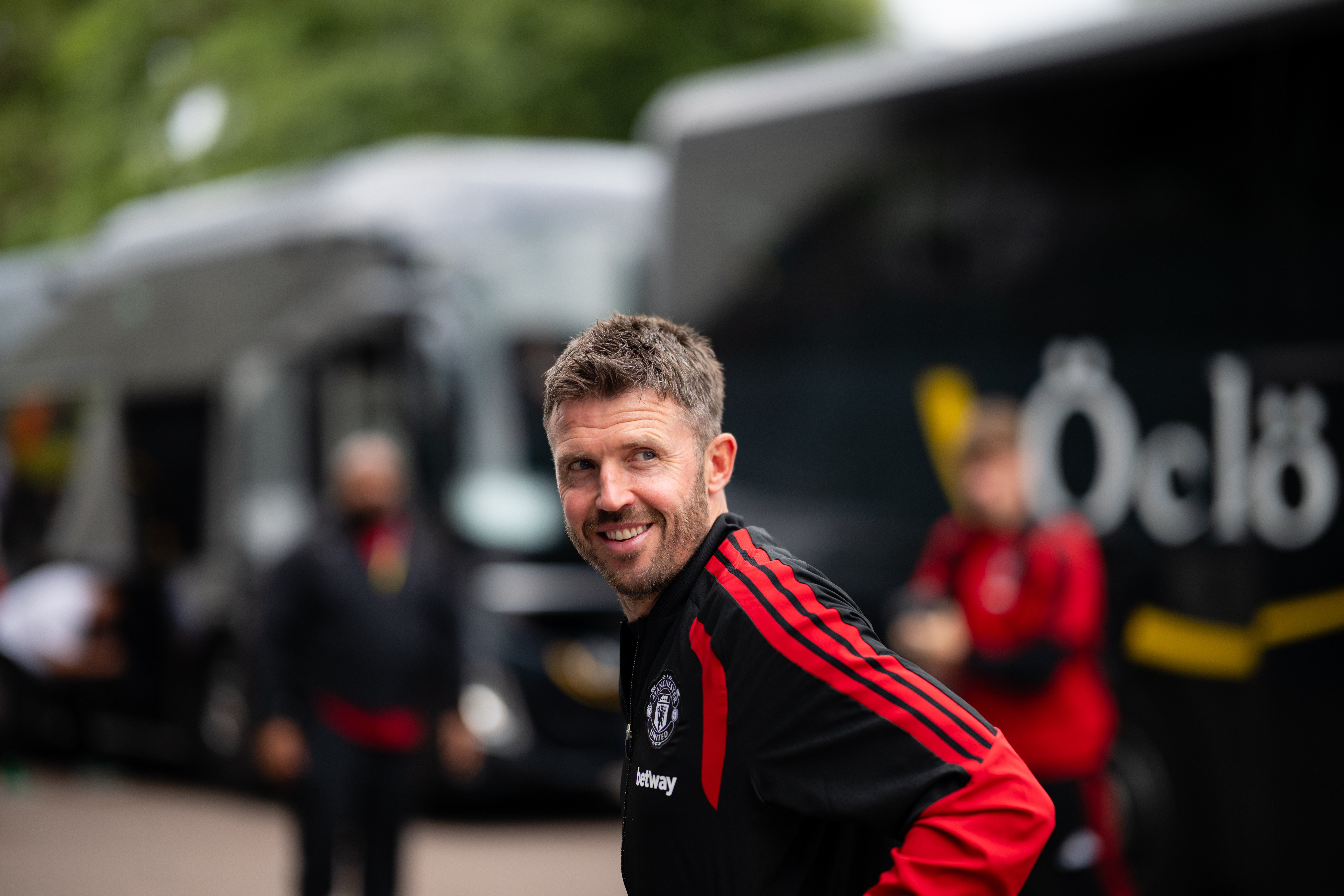 Michael Carrick in front of the coach smiling