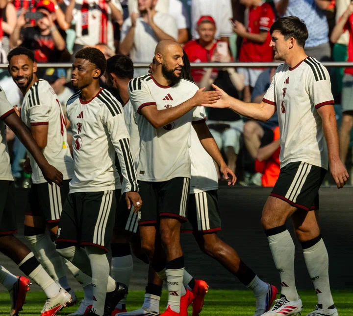 Noussair Mazraoui and Harry Maguire handshake after goal v AC Milan in white kit