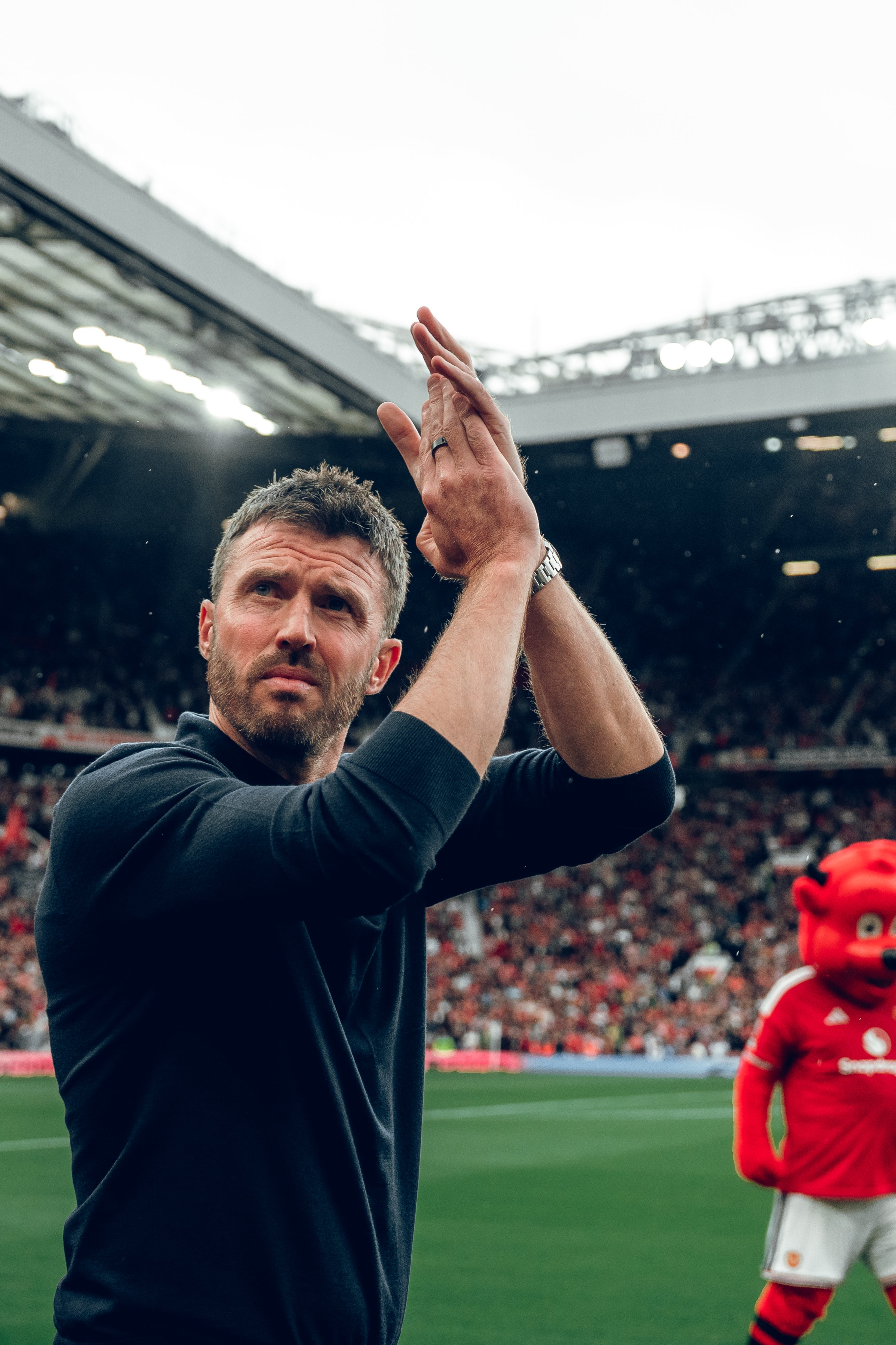 Michael Carrick applauds crowd with Fred the Red in background v Ipswich