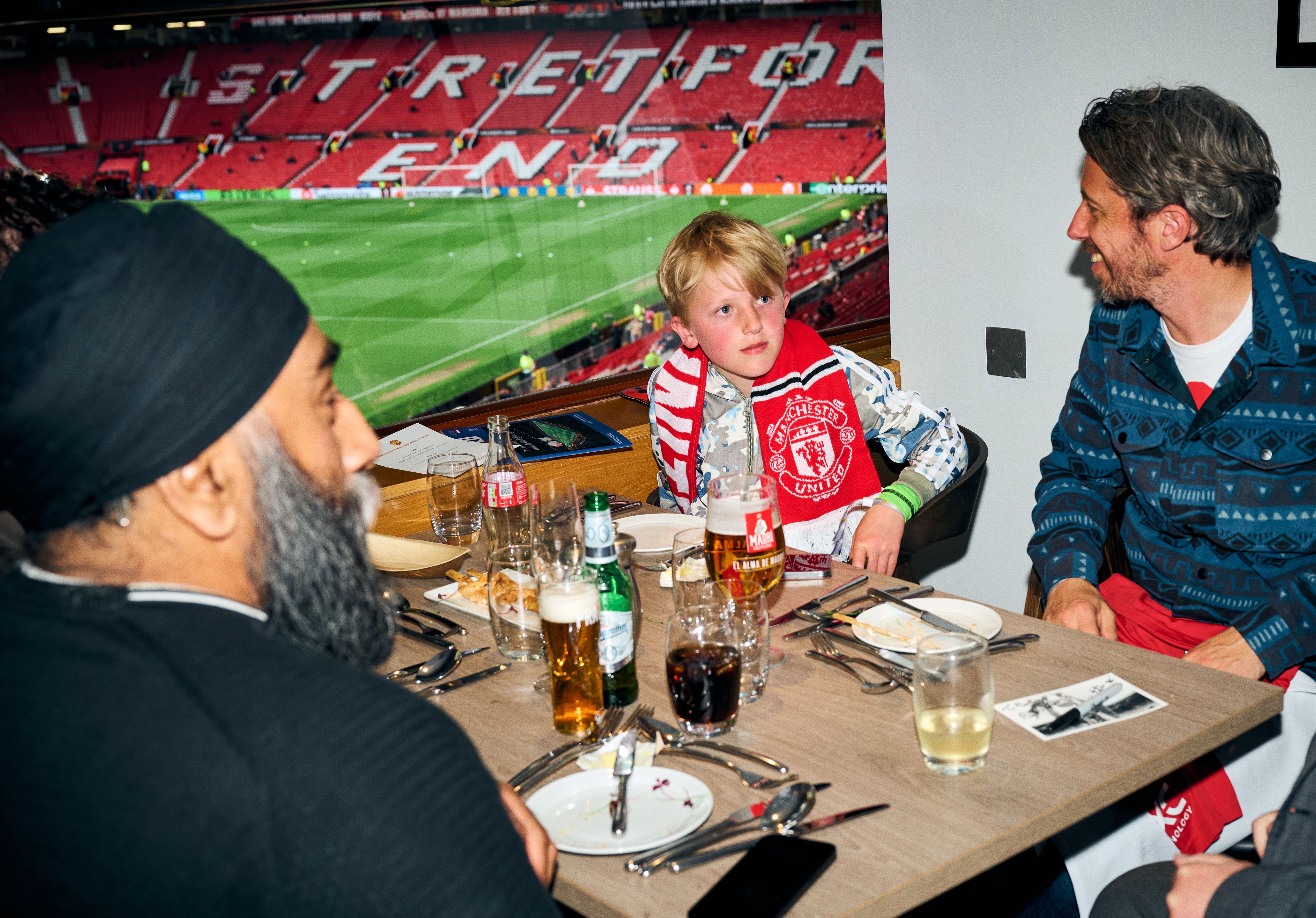 Fans at Matchday Hospitality table with Stretford End in background