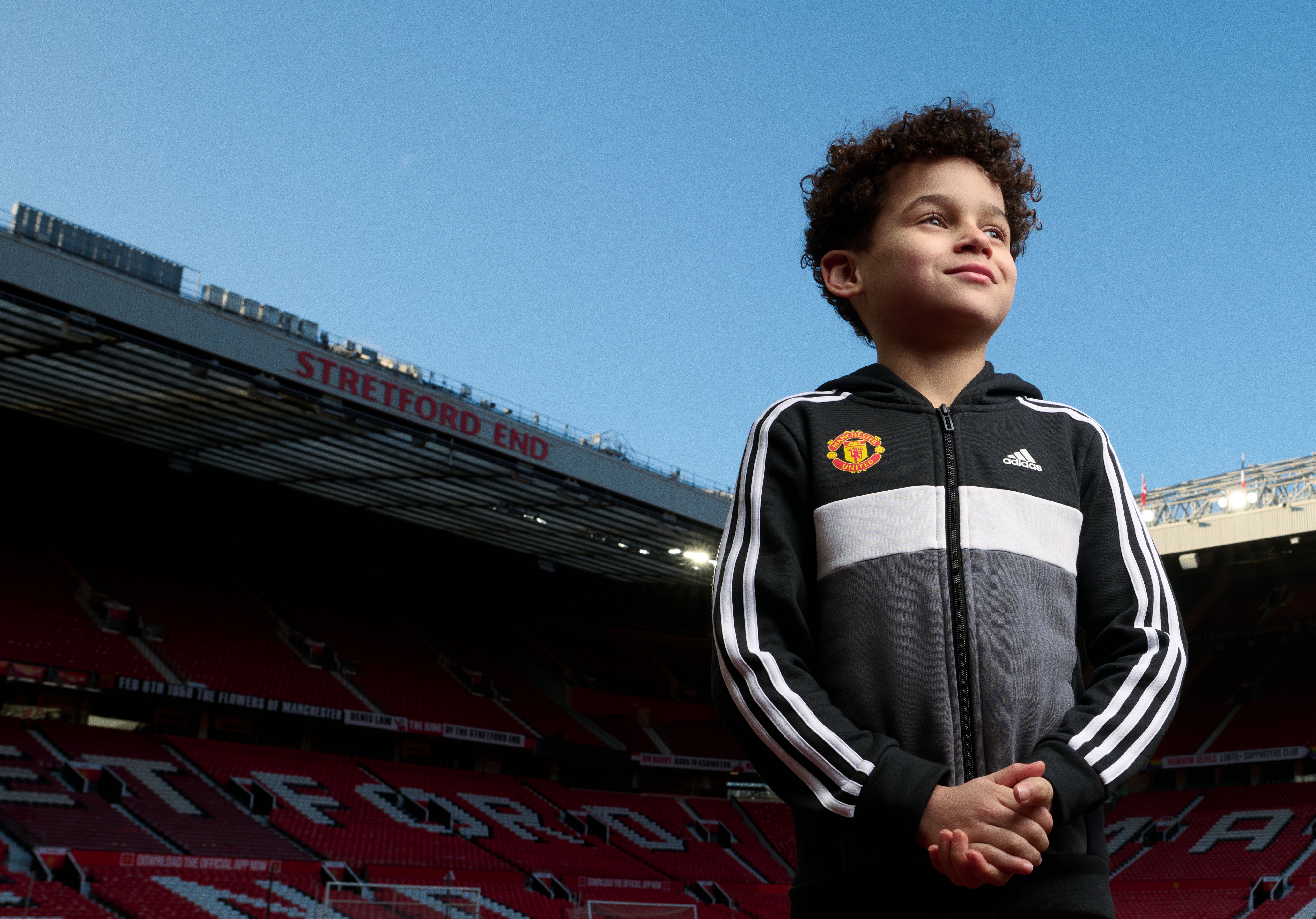 Young fan with hands folded Old Trafford backdrop