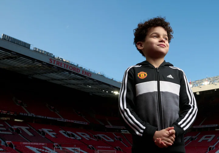Young fan with hands folded Old Trafford backdrop