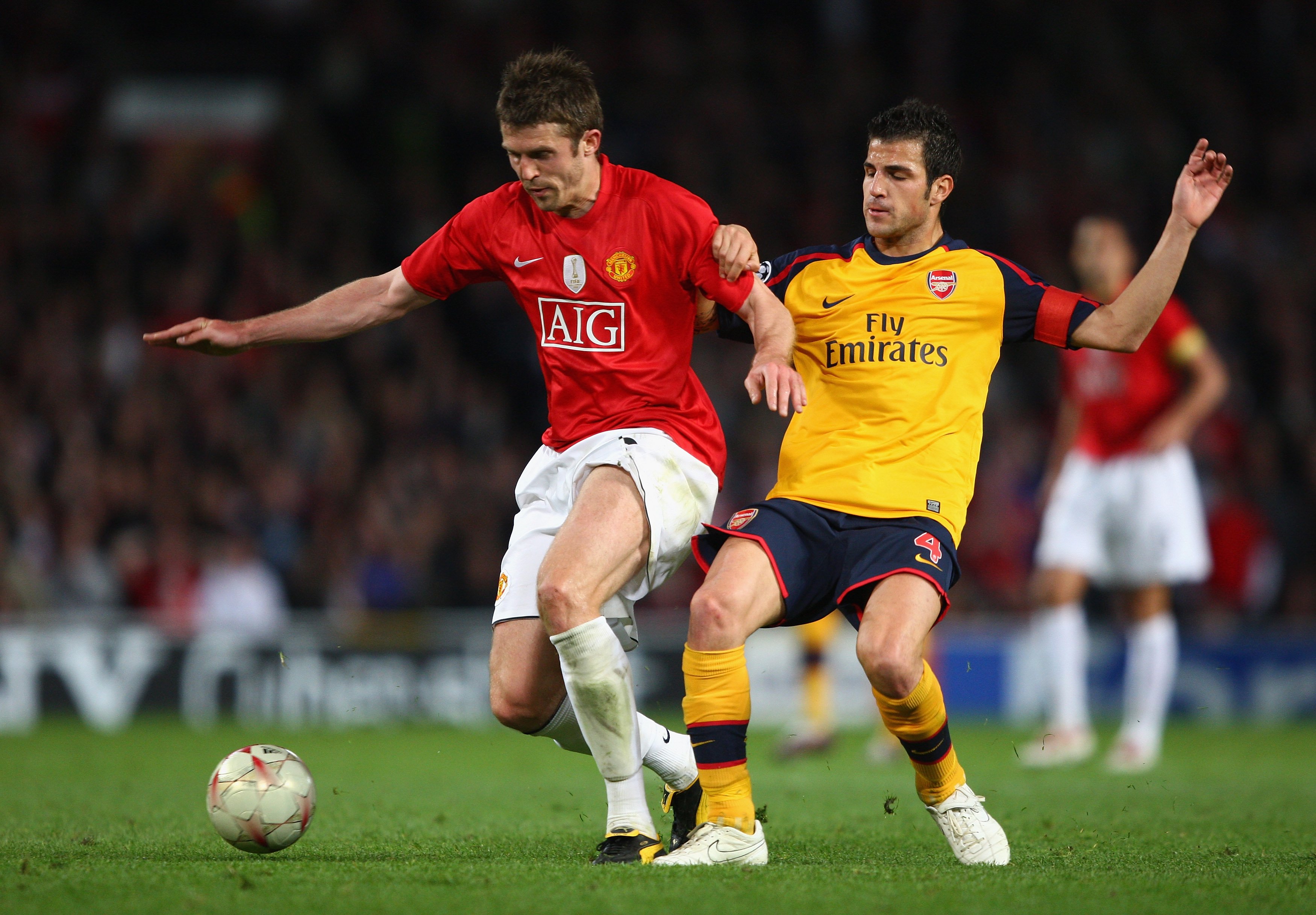Michael Carrick holds off Cesc Fabregas